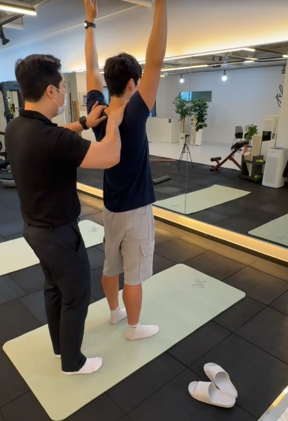 해운대체형교정 안내: 선 자세에서 팔을 들어 올리는 움직임을 함께 확인하는 모습