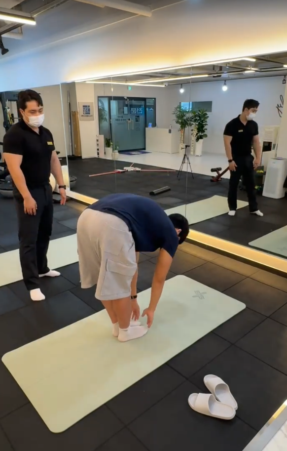 선 자세에서 몸통을 앞으로 숙이는 움직임을 옆에서 확인하는 지도자